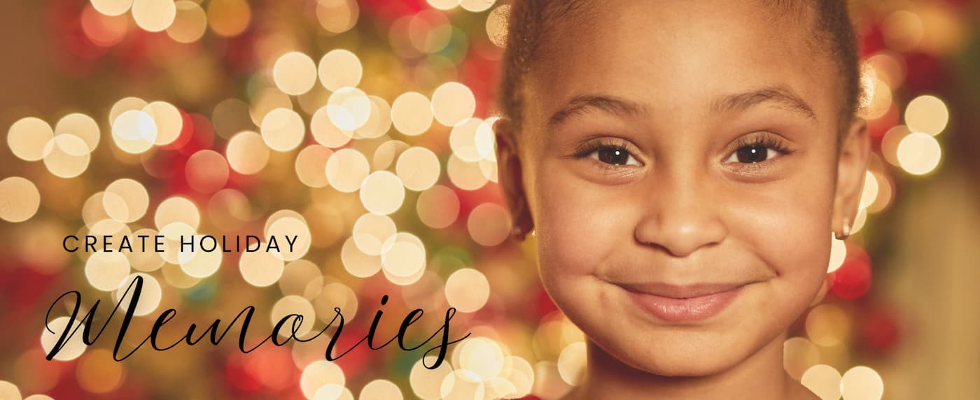 Young girl smiling at the camera in front of a Christmas tree
