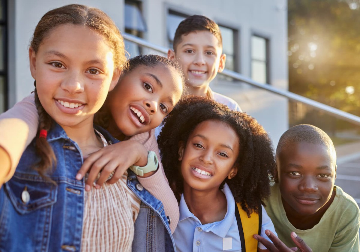 Group of five children smiling together on a stairway outside of a building