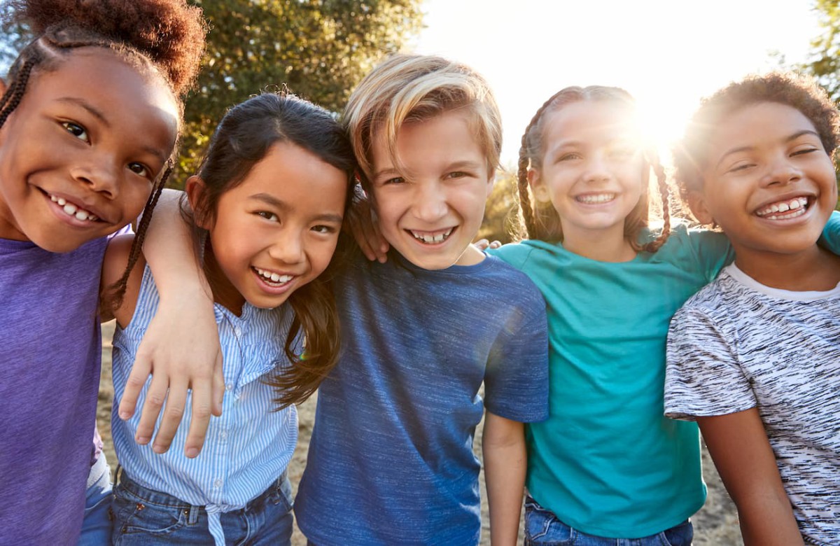 A group of five children smiling outdoors