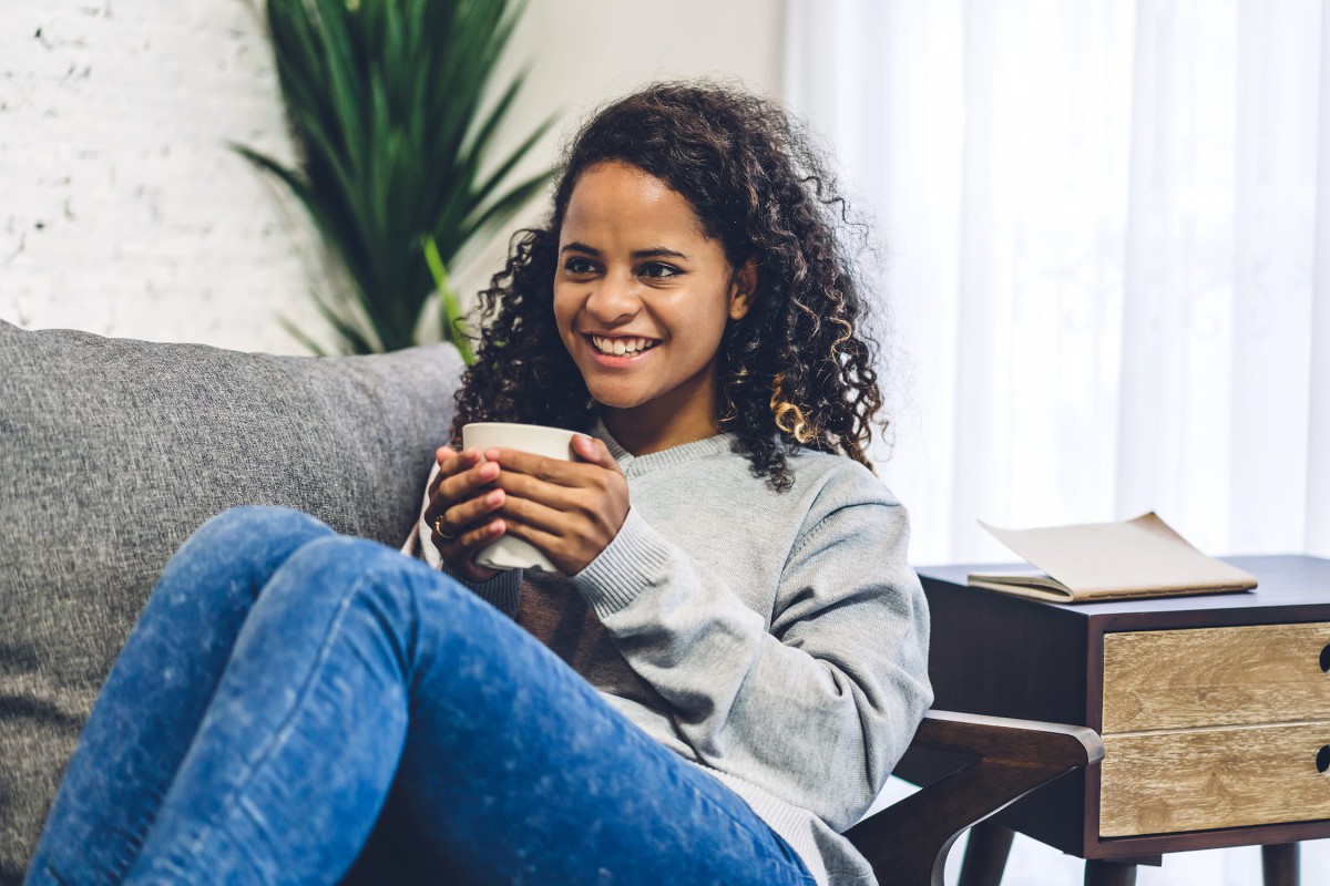 A girl sitting on a couch holding a drink