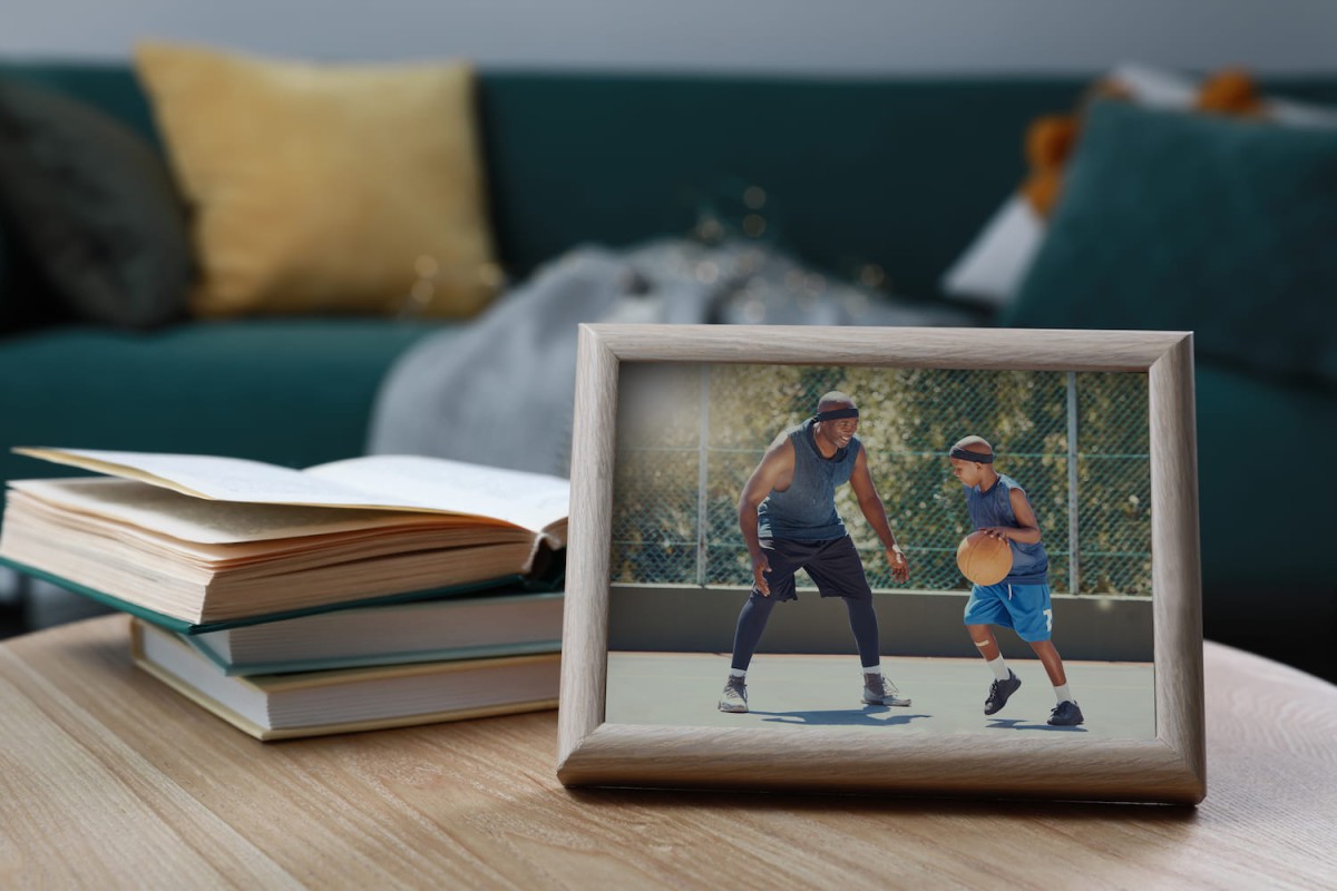 A framed photograph on a table of a child playing basketball with his father