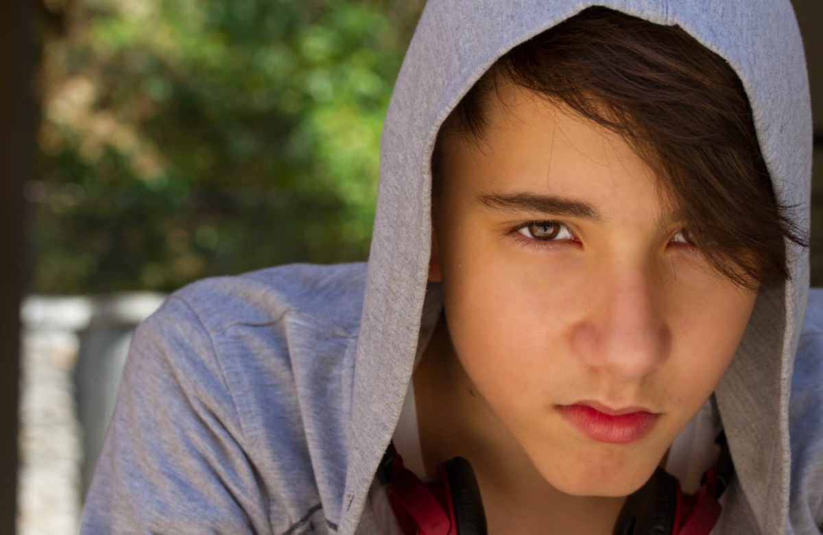A teenager sitting outdoors with a troubled expression