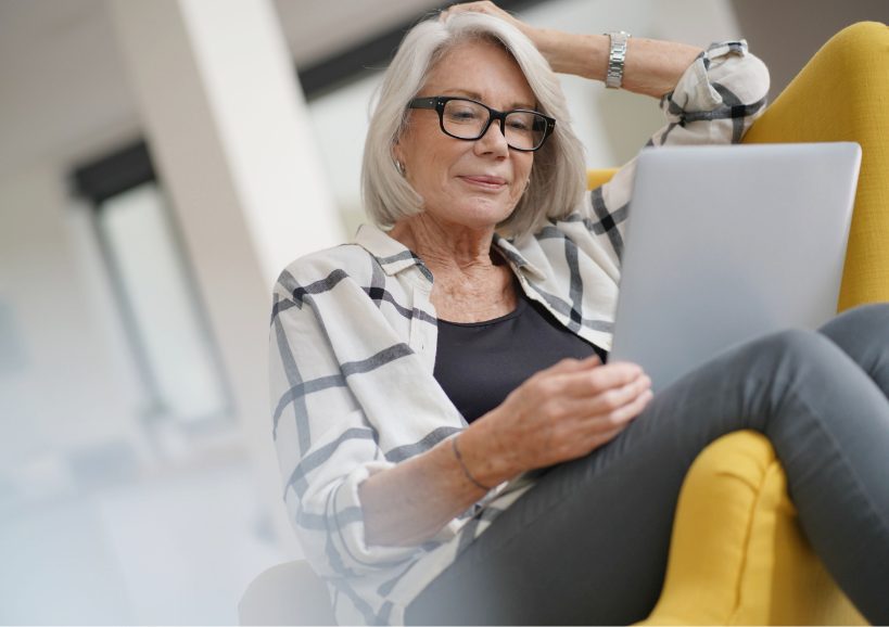 A senior woman sitting in a yellow chair reading a document