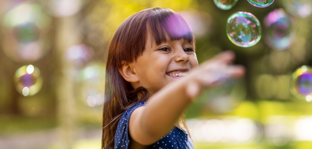 A child playing outdoors with bubbles