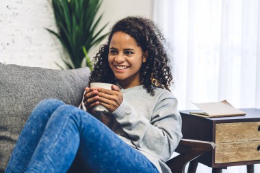 A girl sitting on a couch holding a drink