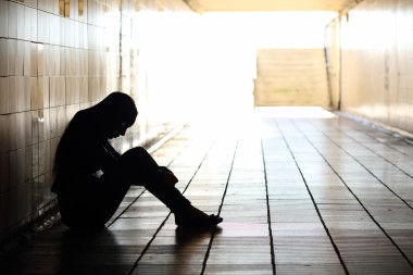 Silhouette of a teenager sitting on the floor in a dark hallway