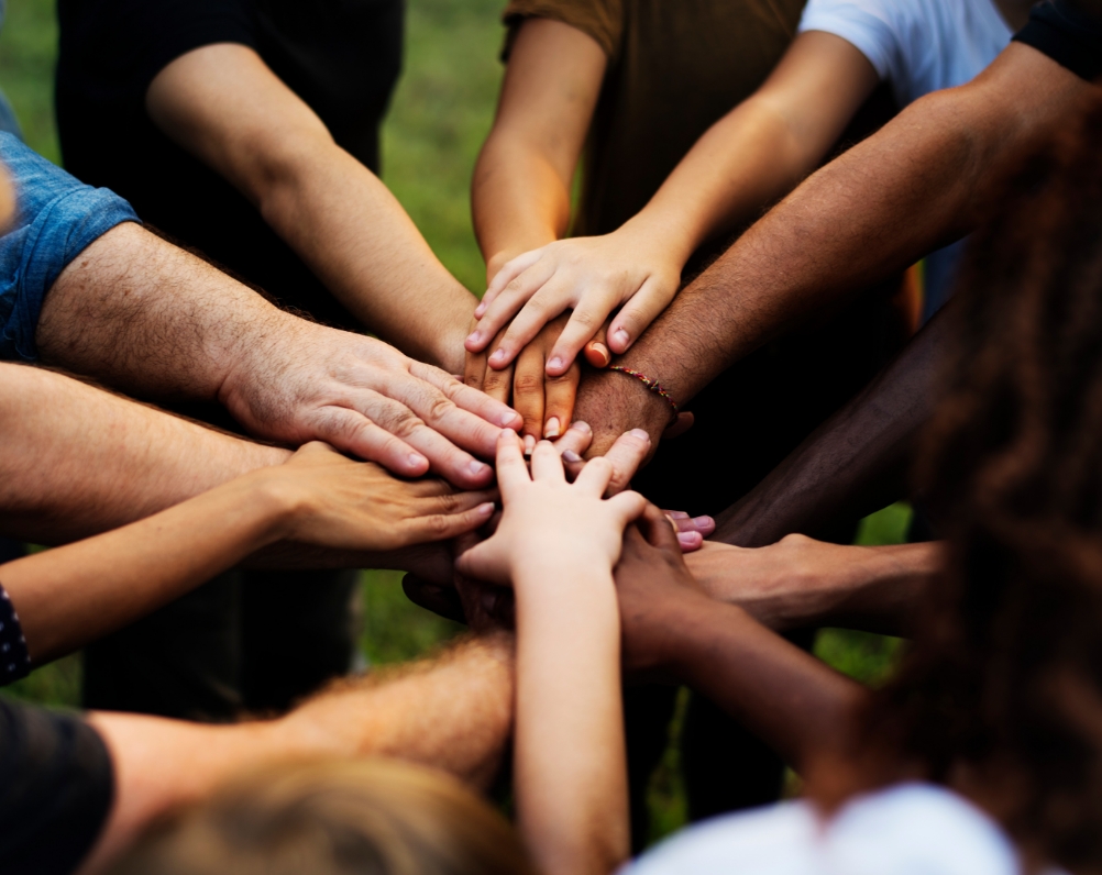 A large group of people in a circle with their hands together