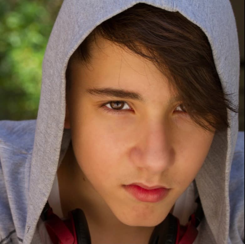 A teenager sitting outdoors with a troubled expression