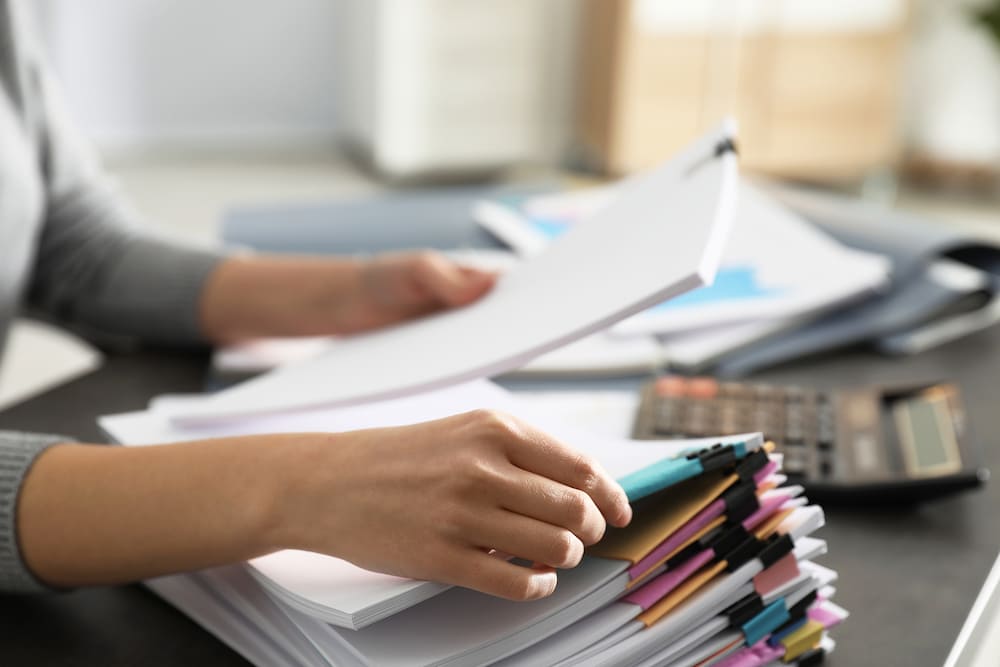 A person reading a document out of a stack of documents