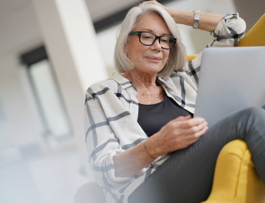 A senior woman sitting on a chair reading a document