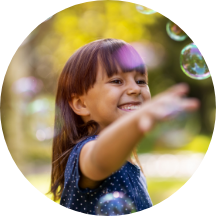 A young girl playing with bubbles outdoors